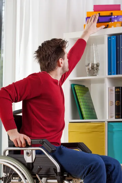 Hombre en silla de ruedas durante la tarea diaria —  Fotos de Stock