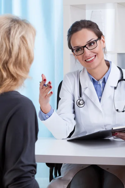 Internist lächelt Patientin an — Stockfoto