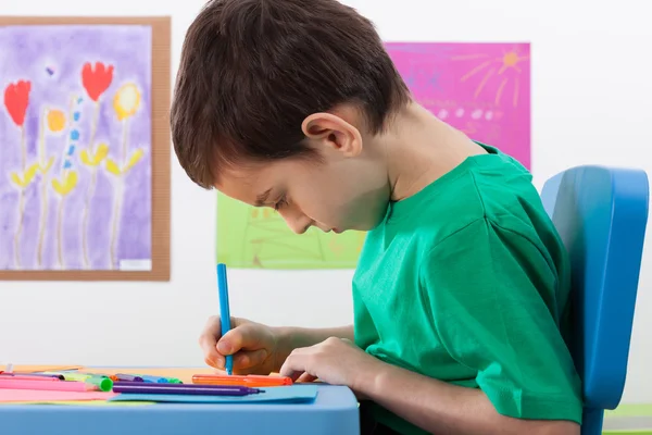 Menino pinta algo com marcadores na escola — Fotografia de Stock