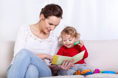 Anne çocuklu kitap okuyor.