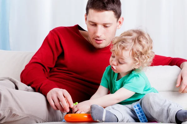 Dad with son sit on the couch and playing — Stock Photo, Image