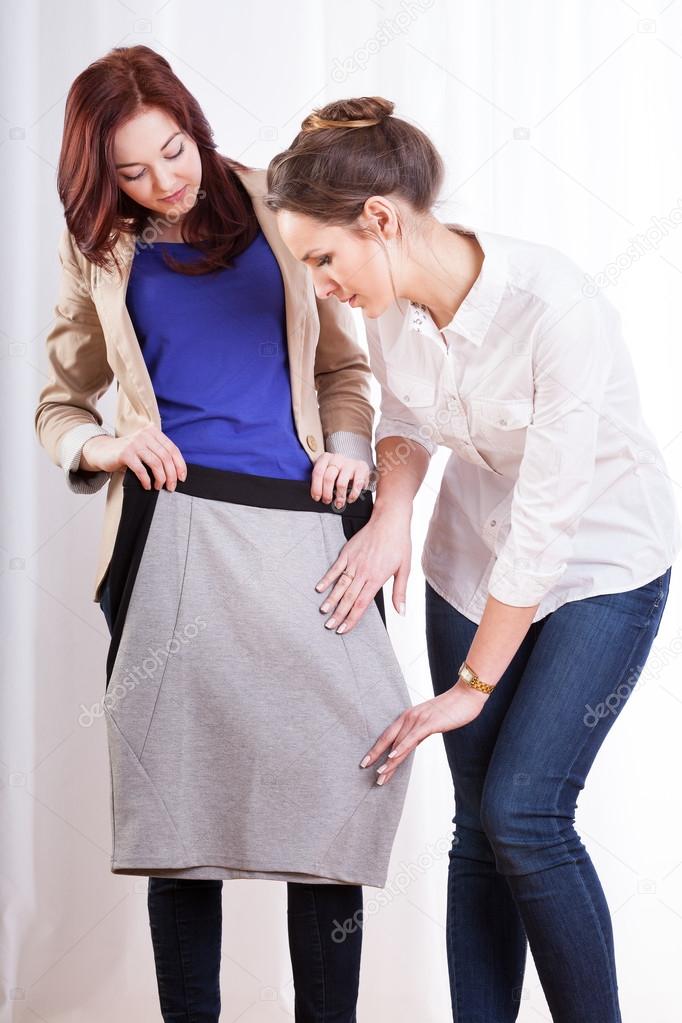 Female friends trying on pencil skirt