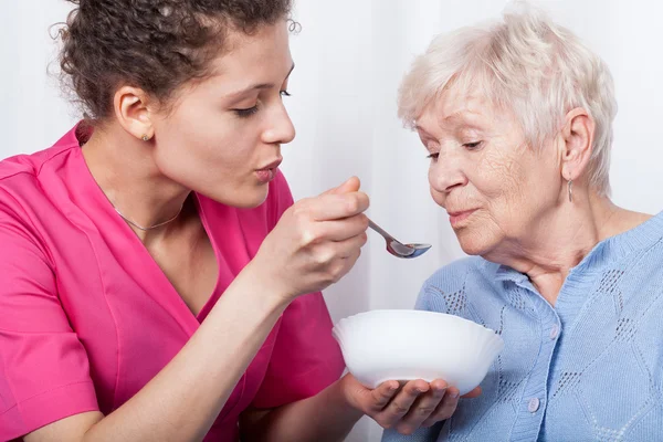 Infermiera alimentando una signora più anziana — Foto Stock