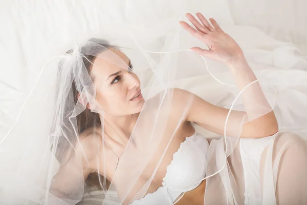 Woman in bridal lingerie covering her face using veil — Stock Photo, Image