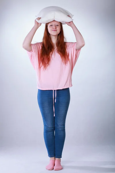 Girl holding pillow above her head — Stock Photo, Image