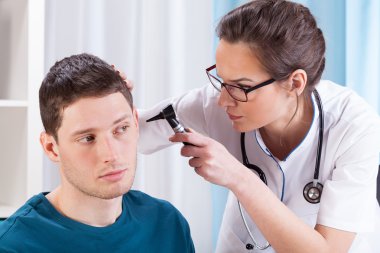 genç doktor hastanın kulakları incelenmesi