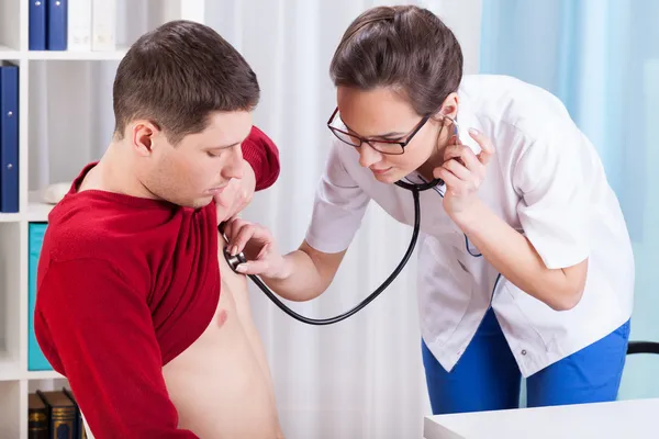 Médico joven examinando el corazón de un paciente — Foto de Stock