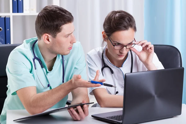 Junge Ärzte nutzen Laptop und sprechen — Stockfoto