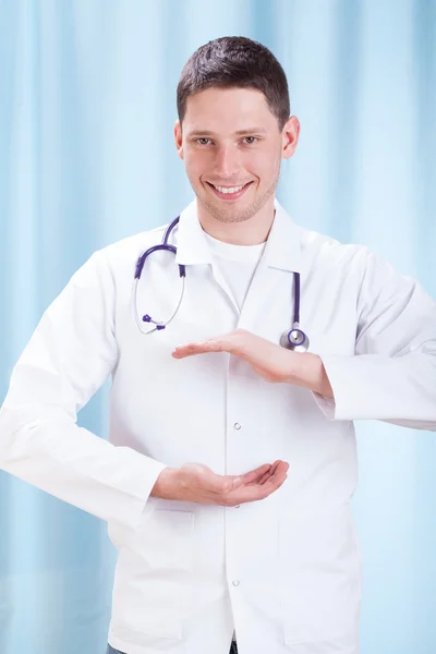 Smiling doctor presents something — Stock Photo, Image