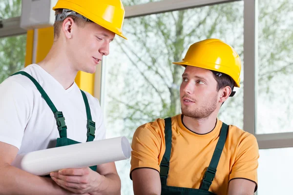 двоє чоловіків у спецодягу та hardhat під час