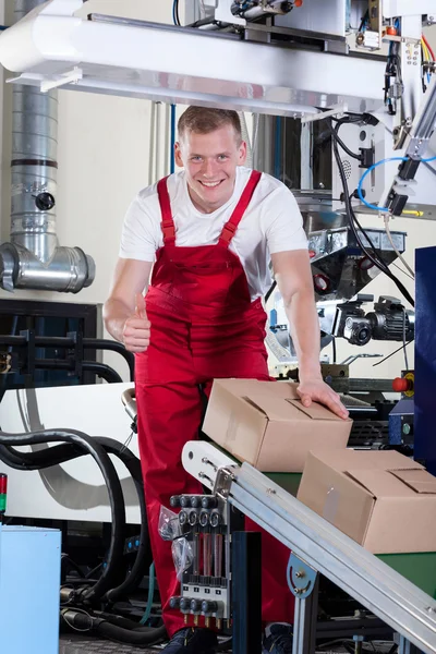 Worker showing thumbs up sign next to conveyor belt — Stock Photo, Image