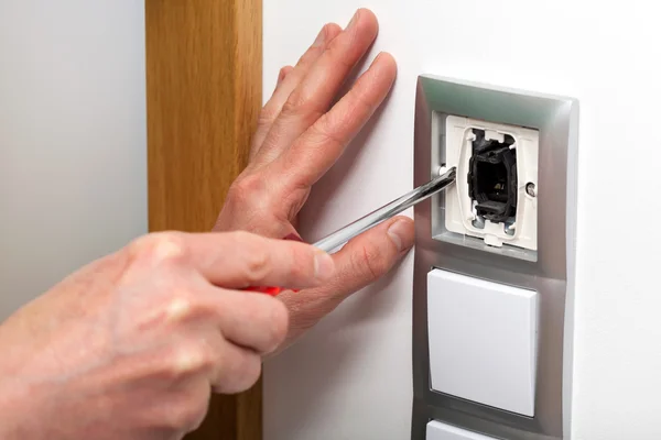 Hands with screwdriver repairing a switch — Stock Photo, Image