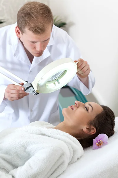 Cosmetologist examining patient's skin — Stock Photo, Image