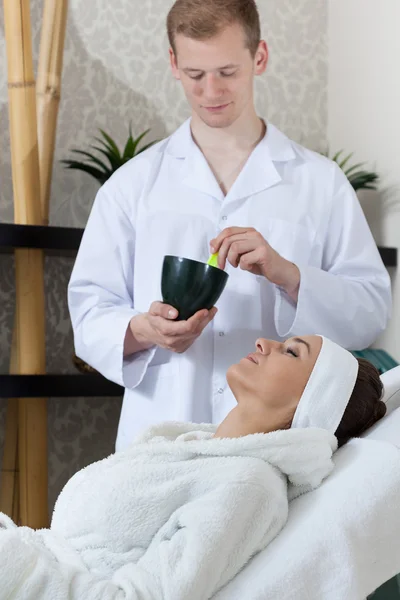 Man preparing facial mask for client — Stock Photo, Image