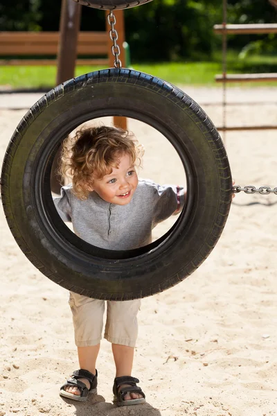 Pojke med däck swing — Stockfoto