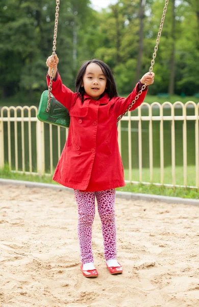 Kleines Mädchen schaukelt auf dem Spielplatz — Stockfoto