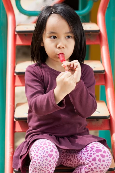 Little girl sitting on the slide — Stock Photo, Image