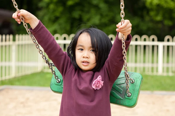 Swing oynarken sevimli küçük kız — Stok fotoğraf