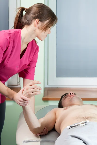 Terapeuta wyciąganie człowieka ramię — Zdjęcie stockowe