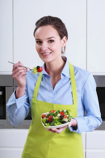 Huisvrouw proeverij salade — Stockfoto