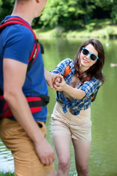 Chico ayudando chica por el lago — Foto de Stock