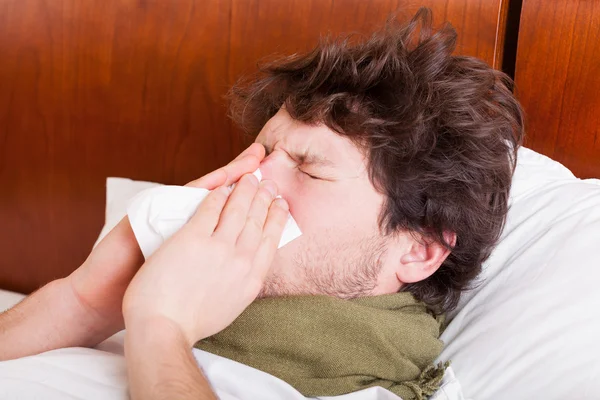 Jonge zieke man waait neus — Stockfoto