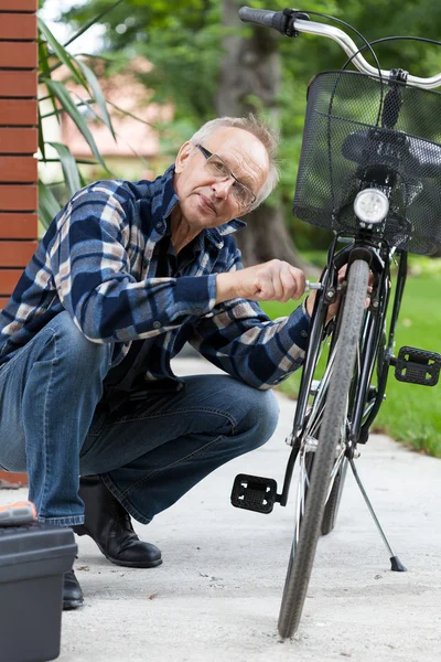 Elderly man fixing bicycle — Stock Photo, Image