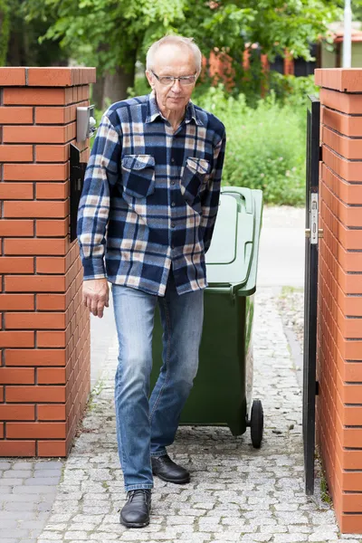 Älterer Mann zieht Müllcontainer auf Rädern — Stockfoto