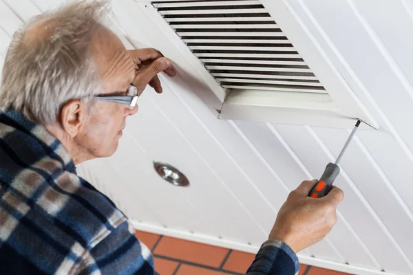 Homem apertando os parafusos na grade de ventilação — Fotografia de Stock