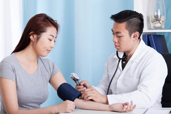 Médico asiático tomando pressão arterial de um paciente — Fotografia de Stock