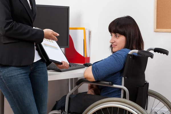 Vrouw op rolstoel analyseren van grafieken met haar baas — Stockfoto