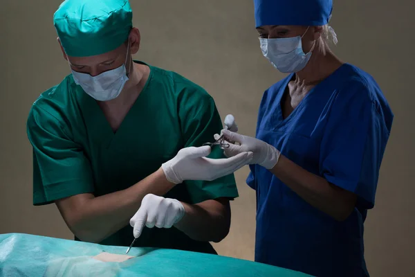 Médico e assistente durante a cirurgia — Fotografia de Stock