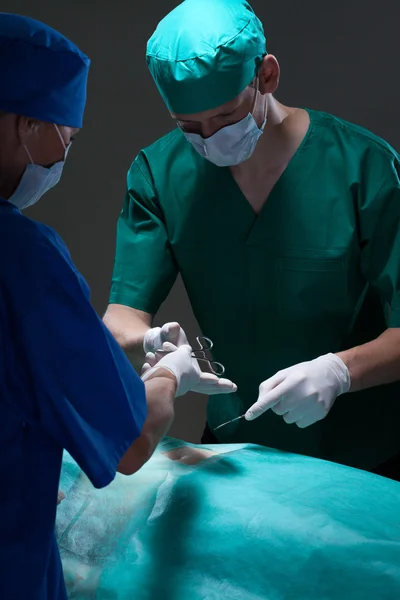 Assistente ajudando cirurgião com cirurgia — Fotografia de Stock