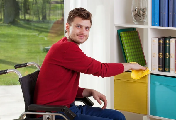 Stanie niepełnosprawny mężczyzna wycierać kurz — Zdjęcie stockowe