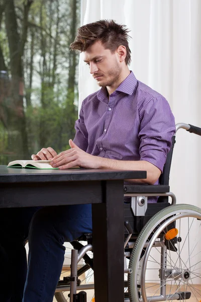 Homem com deficiência lendo um livro em casa — Fotografia de Stock