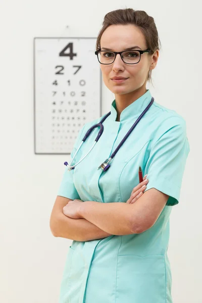 Kendine güvenen Bayan optometrist kolları ile ayakta geçti — Stok fotoğraf