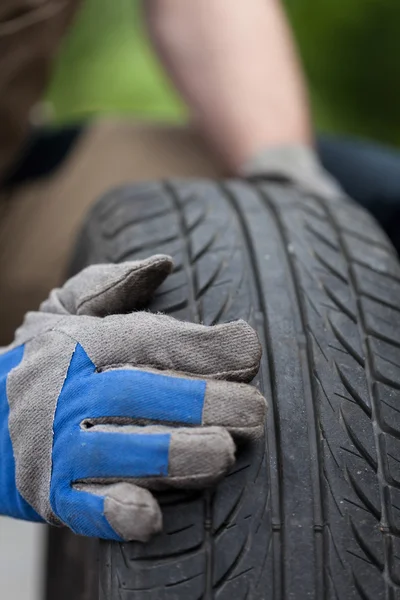 Mãos mecânicas e pneu do carro — Fotografia de Stock
