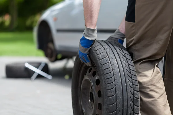 Man rolling a spare wheel — Stock Photo, Image