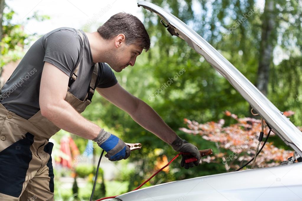 Mechanic using jumper cables to start a car battery — Stock Photo
