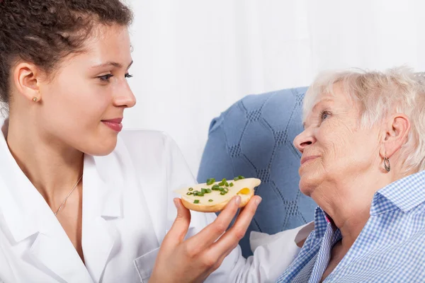 Infermiera che allatta donna anziana — Foto Stock