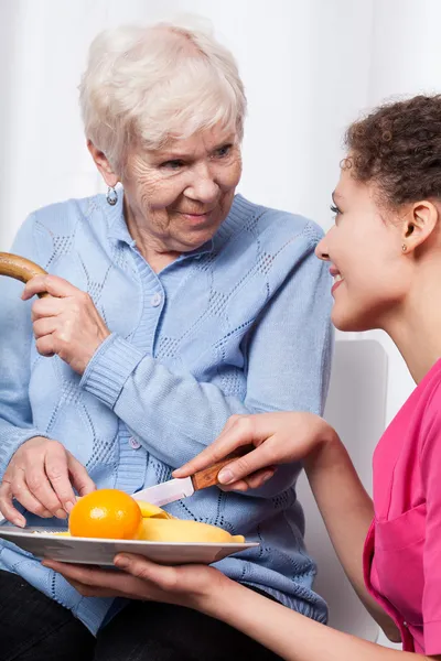 Enfermeira e idosa comendo frutas — Fotografia de Stock