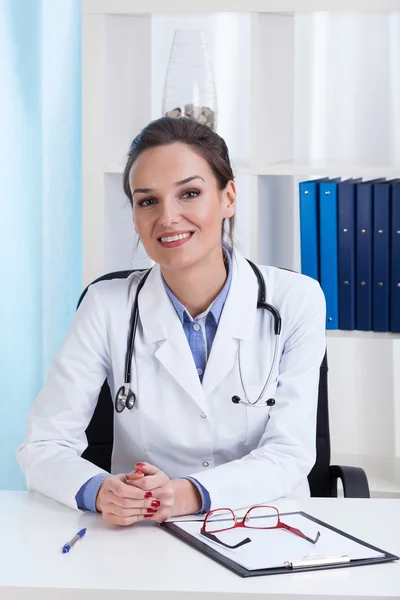 Smiling lady doctor sitting at desk — Stock Photo, Image