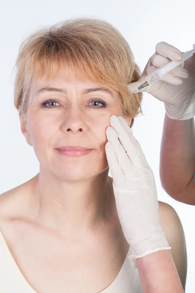 Doctor does injection to elderly woman's face — Stock Photo, Image