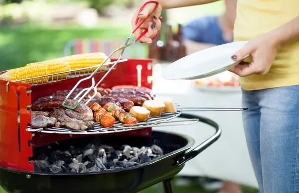 Woman dishing up grilled meals — Stock Photo, Image
