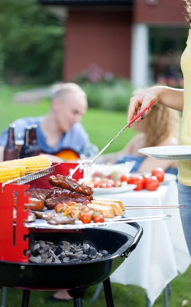 Woman serving grilled sausages — Stock Photo, Image