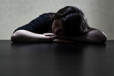 dalgın ve üzgün bir kız başını masaya koyarak