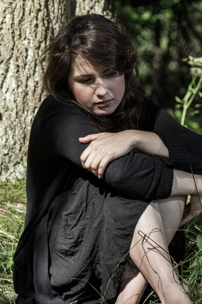 Troubled woman sitting under the tree — Stock Photo, Image