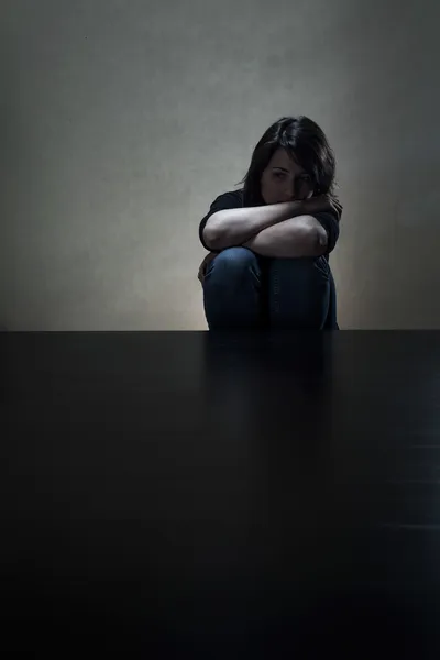 Girl sitting alone in dark room — Stock Photo, Image