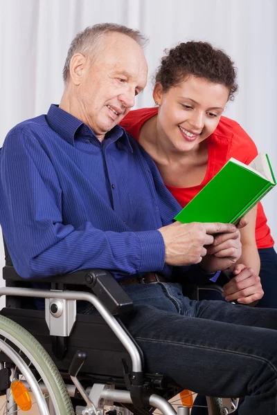 Behinderte und eine Krankenschwester lesen gemeinsam ein Buch — Stockfoto