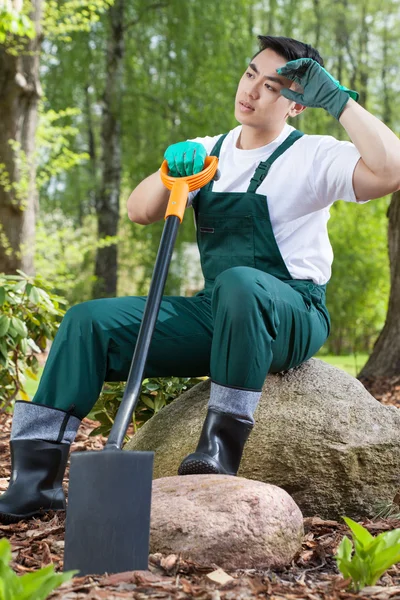 Utmattad trädgårdsmästare vilar på en sten — Stockfoto